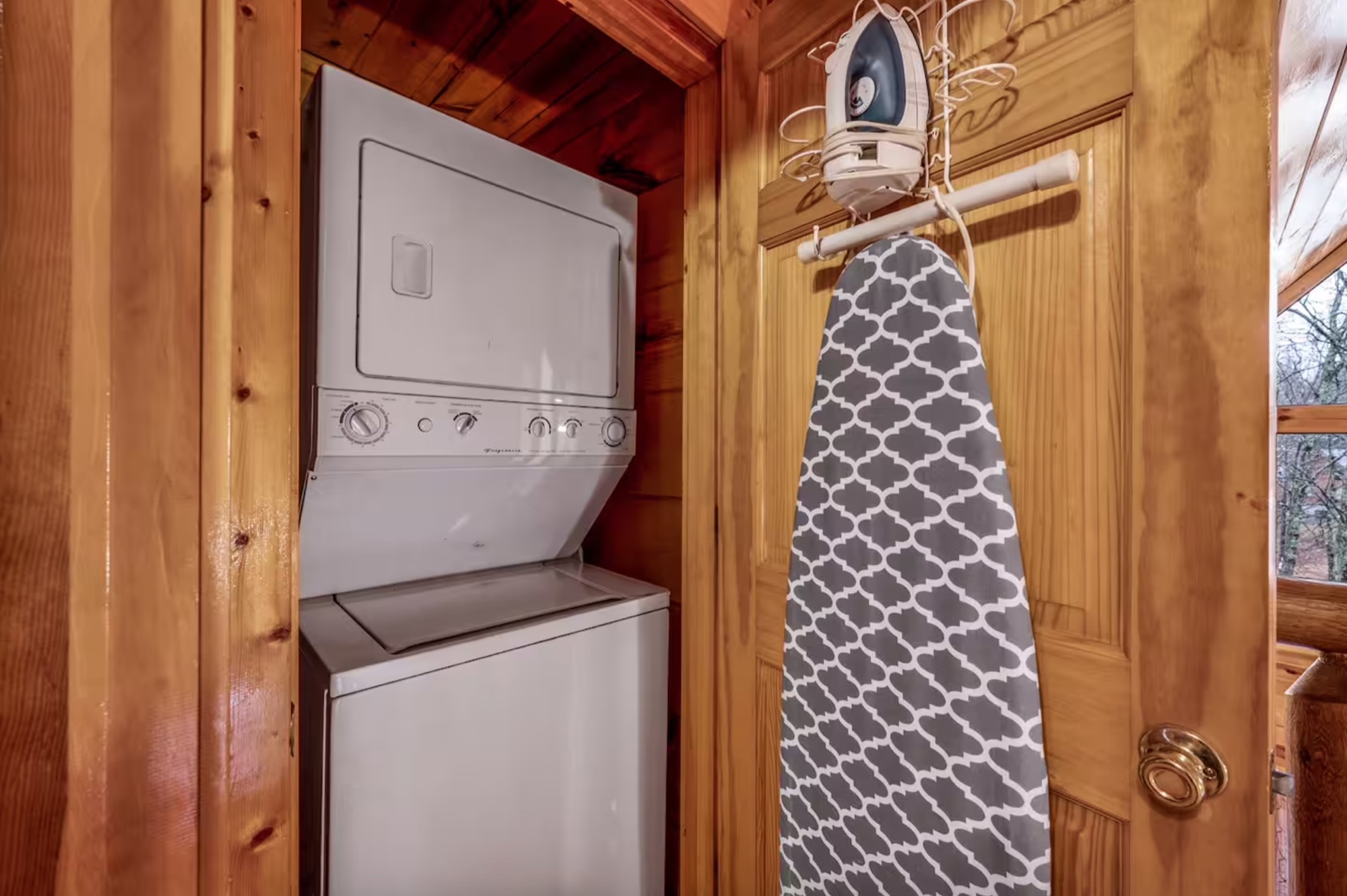 Laundry closet at Bearadise with a stacked washer and dryer and a hanging ironing board